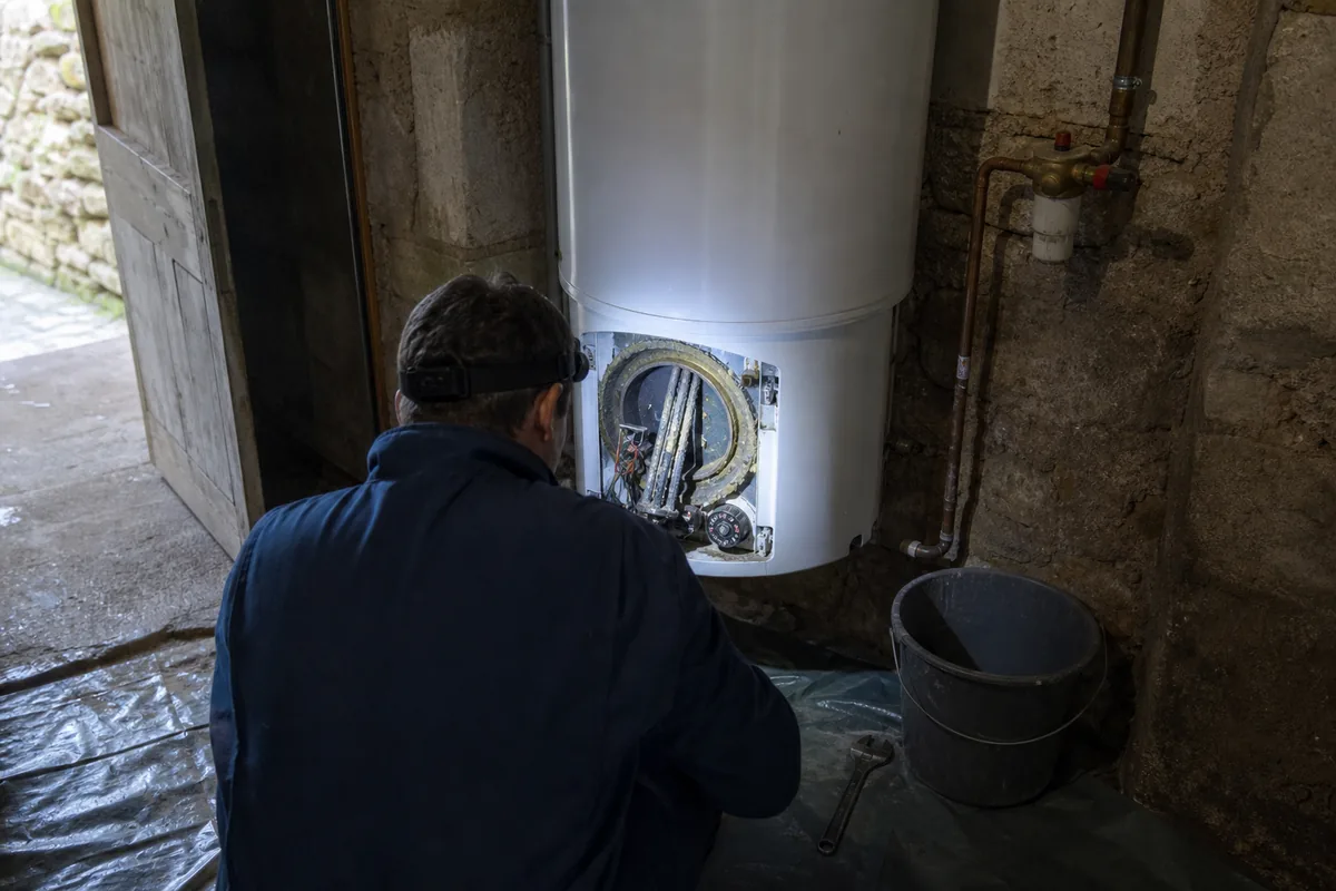 Chauffe-eau ouvert dans un cellier de maison normande, sol protégé par une bâche