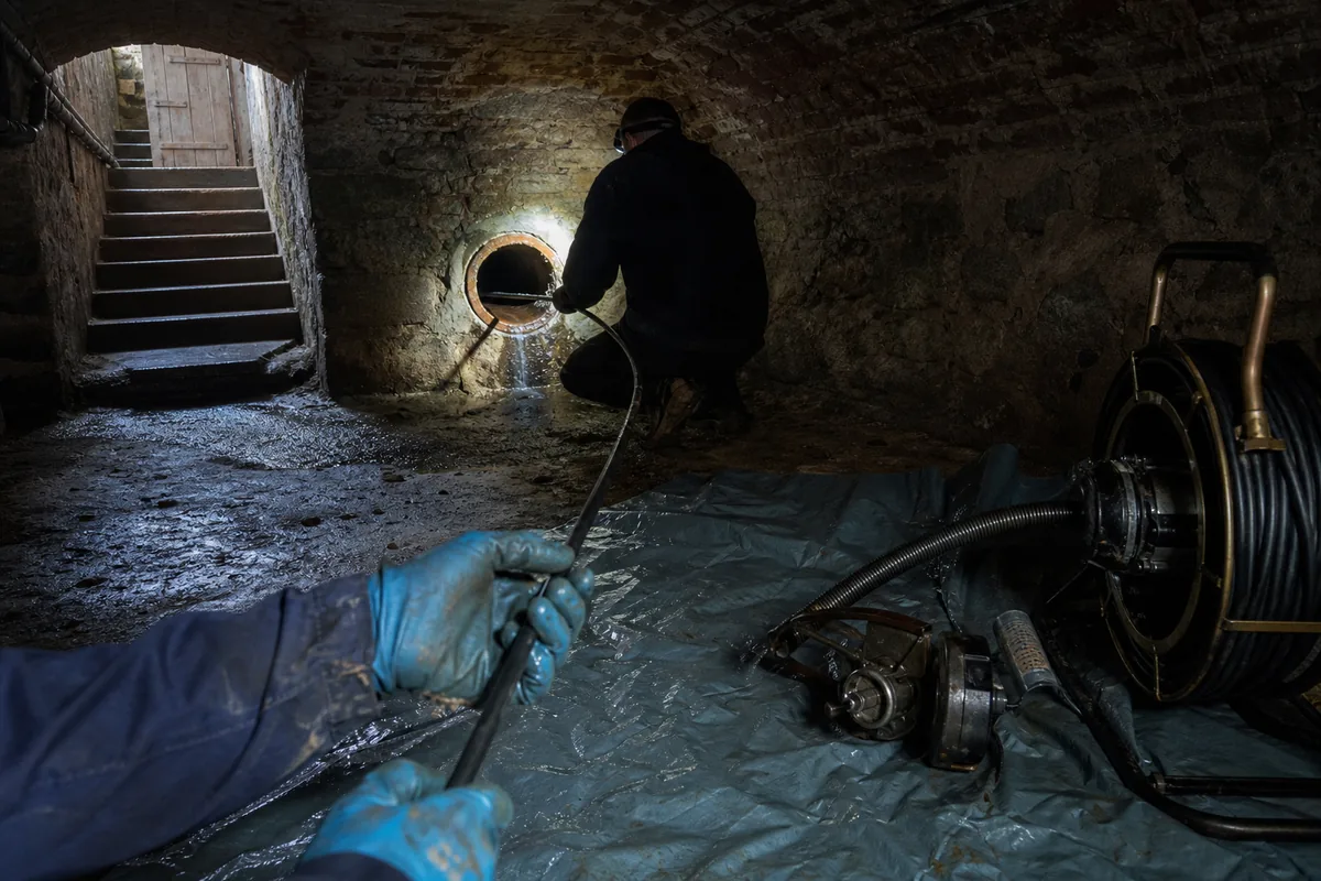 Inspection d&rsquo;un collecteur en grès dans la cave voûtée d&rsquo;une maison en brique
